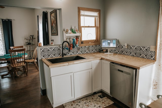 kitchen with white cabinetry, dark wood-style flooring, a sink, stainless steel dishwasher, and butcher block counters