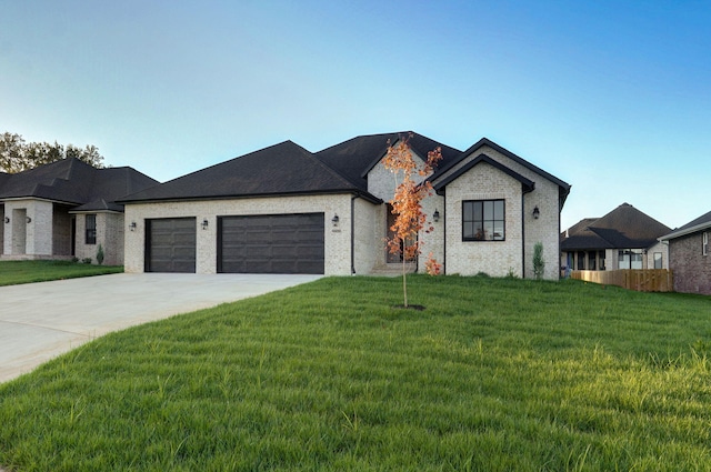 view of front facade with brick siding, a front lawn, concrete driveway, and an attached garage