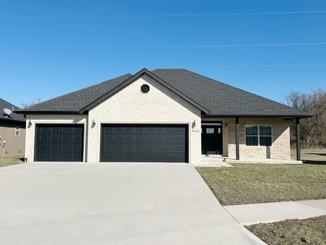 view of front of house with an attached garage, a front yard, driveway, and roof with shingles