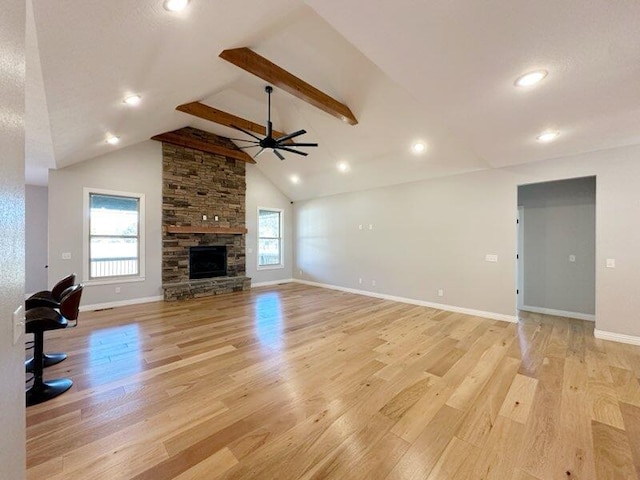 unfurnished living room with a ceiling fan, light wood-style flooring, a fireplace, and beamed ceiling