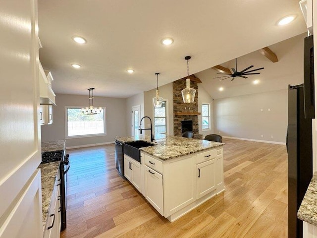 kitchen featuring a sink, light wood finished floors, open floor plan, and white cabinetry