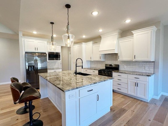 kitchen featuring premium range hood, a sink, range with gas cooktop, stainless steel microwave, and black fridge