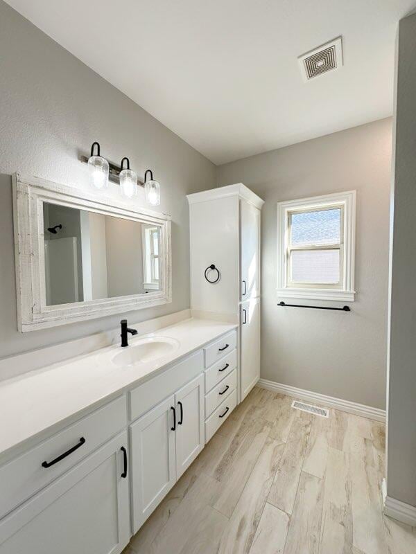 bathroom featuring vanity, wood finished floors, baseboards, and visible vents