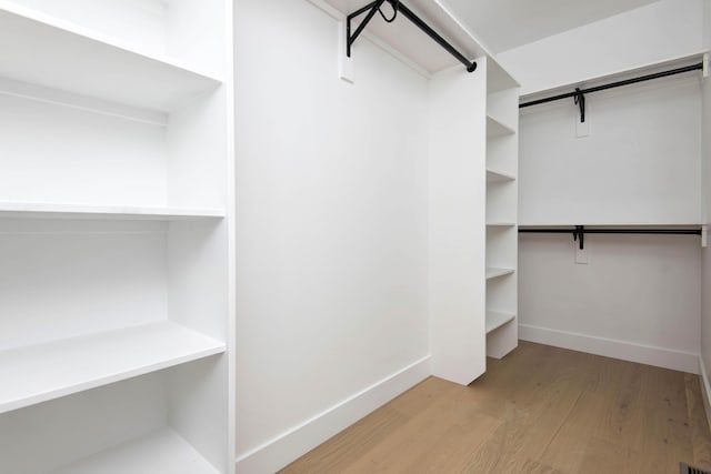 walk in closet featuring a barn door and wood finished floors