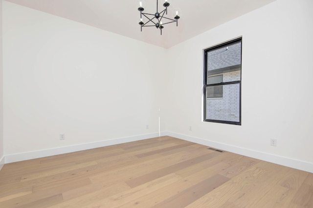 unfurnished room with a notable chandelier, visible vents, and light wood-style floors