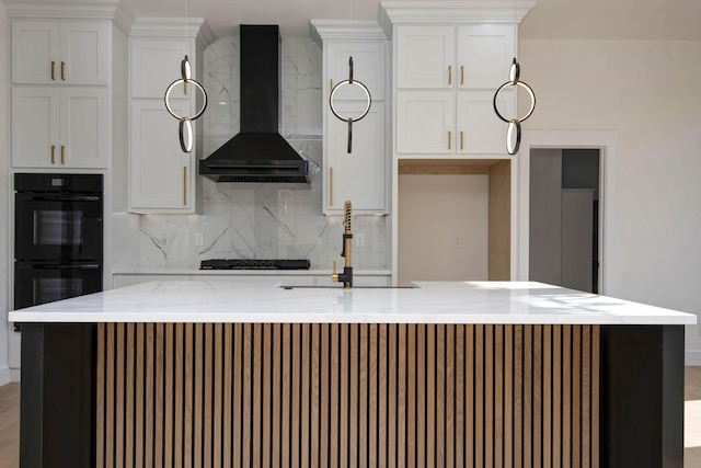 kitchen featuring tasteful backsplash, black appliances, wall chimney range hood, white cabinetry, and a kitchen island with sink