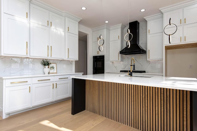 kitchen with wall chimney exhaust hood, dobule oven black, and white cabinets