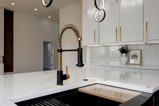 interior details with light stone counters, decorative backsplash, white cabinets, and recessed lighting