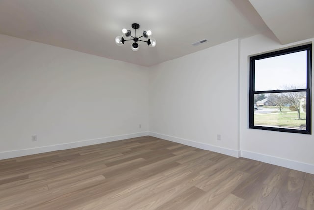 spare room with visible vents, baseboards, a notable chandelier, and light wood-style flooring