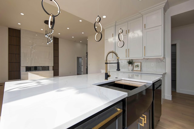 kitchen featuring decorative light fixtures, backsplash, white cabinets, light stone countertops, and dishwasher