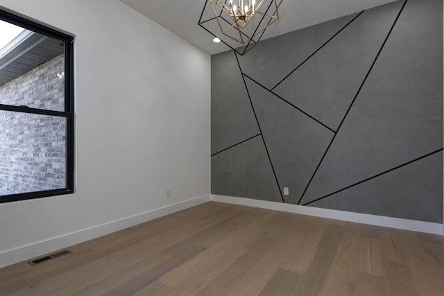 spare room featuring visible vents, wood finished floors, recessed lighting, baseboards, and a chandelier