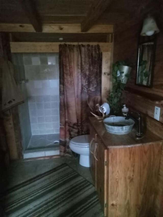 bathroom with beam ceiling, a stall shower, toilet, and vanity