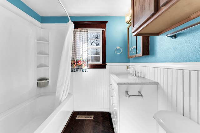 full bathroom with visible vents, shower / bath combo, wood finished floors, wainscoting, and vanity