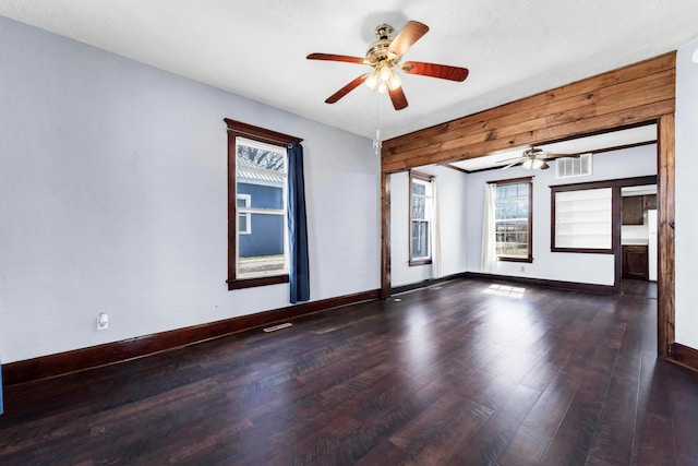 unfurnished room featuring wood finished floors, baseboards, visible vents, and ceiling fan