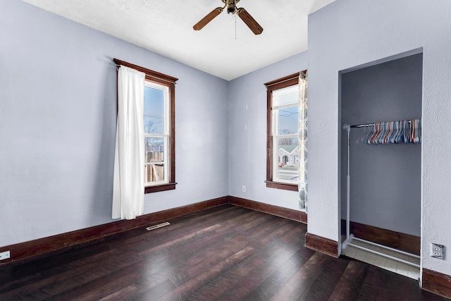 spare room with baseboards, wood finished floors, visible vents, and ceiling fan