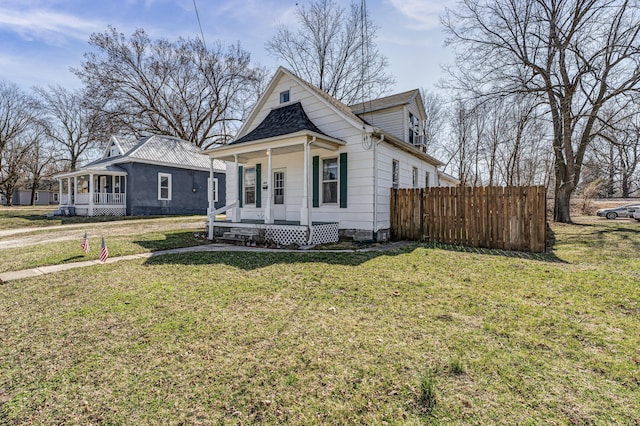 view of front of home with covered porch, a front lawn, and fence