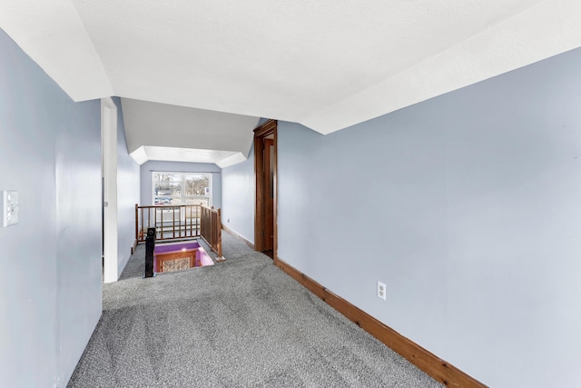 corridor with carpet, lofted ceiling, an upstairs landing, and baseboards