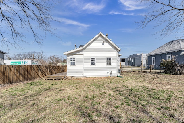 rear view of house with fence and a lawn