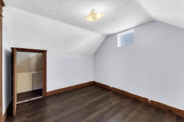 bonus room with dark wood finished floors, a textured ceiling, lofted ceiling, and baseboards