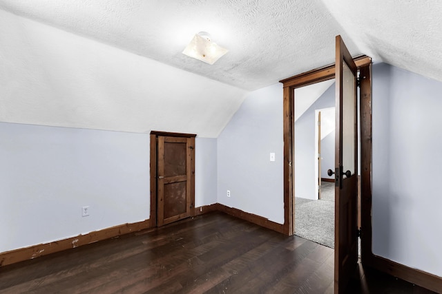 bonus room with dark wood-style floors, a textured ceiling, baseboards, and vaulted ceiling