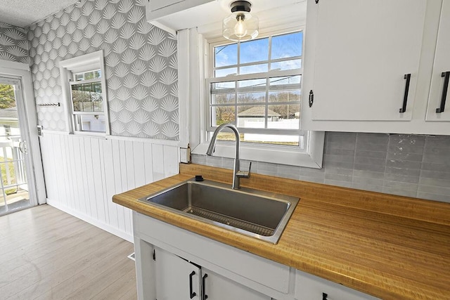 kitchen with a sink, plenty of natural light, light wood-style flooring, and white cabinetry