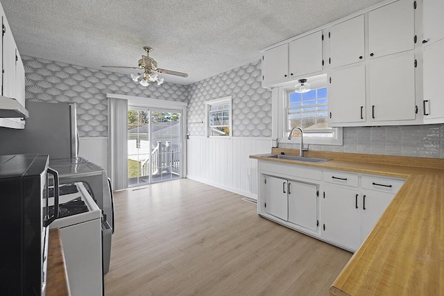 kitchen with wallpapered walls, ceiling fan, washer / dryer, wainscoting, and a sink