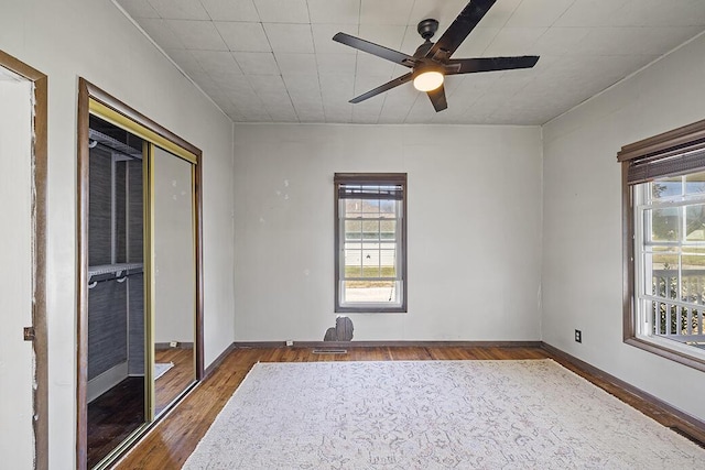 unfurnished room featuring a wealth of natural light, baseboards, ceiling fan, and wood finished floors