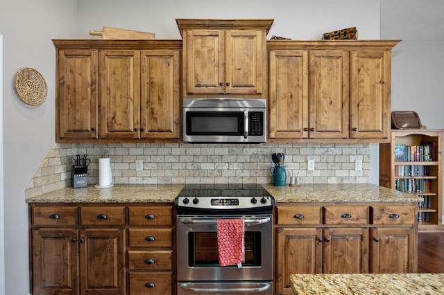 kitchen with decorative backsplash, light stone countertops, brown cabinets, and appliances with stainless steel finishes