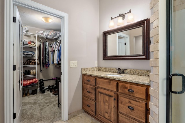 full bath featuring vanity, a spacious closet, and baseboards