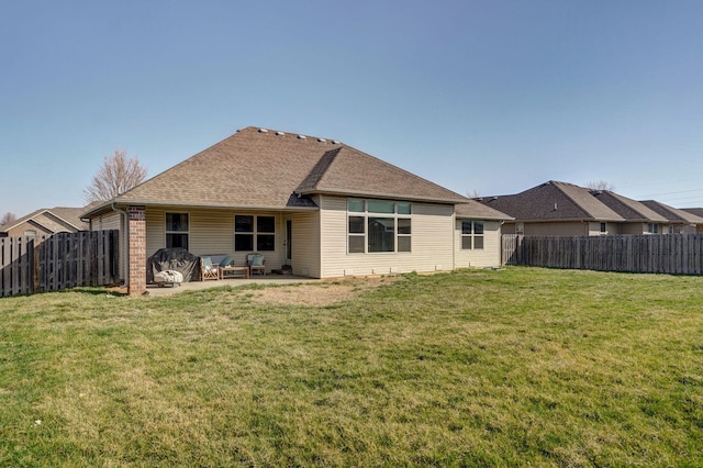 back of house with a yard, a fenced backyard, a patio, and roof with shingles