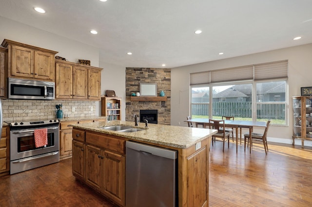 kitchen with dark wood-type flooring, a sink, light stone counters, tasteful backsplash, and stainless steel appliances