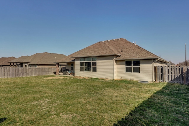 back of property featuring a lawn, a fenced backyard, and roof with shingles