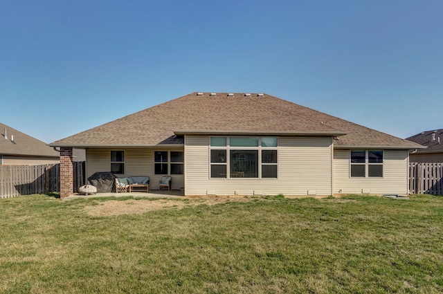 rear view of house featuring a yard, a shingled roof, a fenced backyard, and a patio area