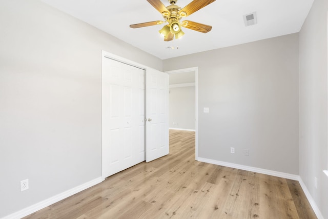 unfurnished bedroom featuring light wood-type flooring, baseboards, a closet, and visible vents