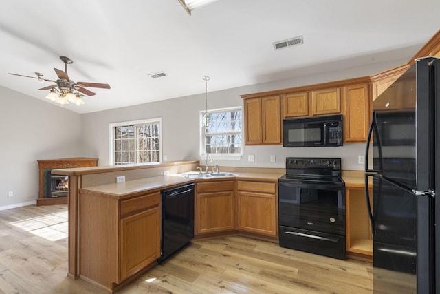 kitchen with black appliances, a peninsula, visible vents, and a sink