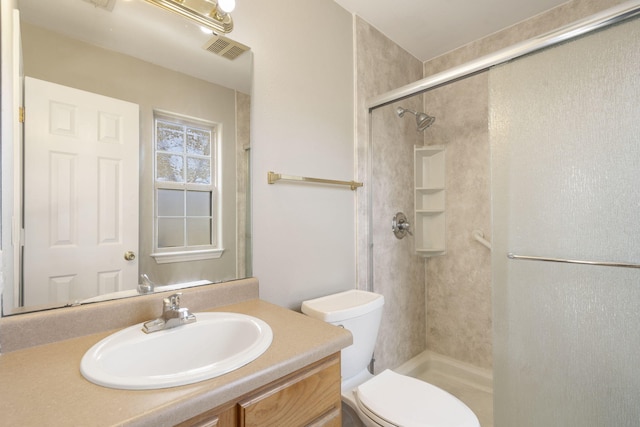 bathroom with vanity, a shower stall, toilet, and visible vents