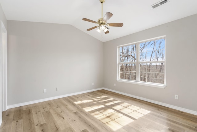 spare room with visible vents, light wood-type flooring, baseboards, and vaulted ceiling