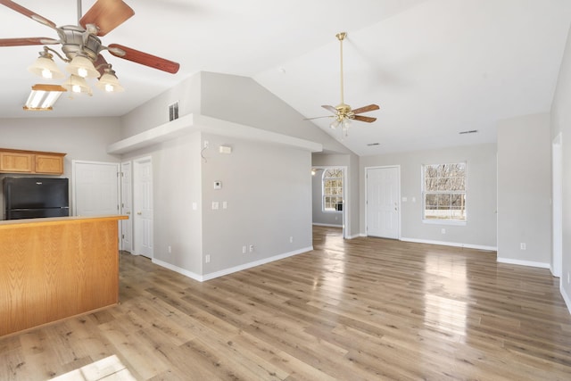 unfurnished living room with light wood-style flooring, baseboards, a ceiling fan, and vaulted ceiling