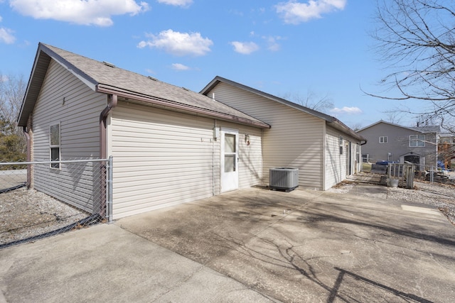 back of property with a patio area, cooling unit, a shingled roof, and fence