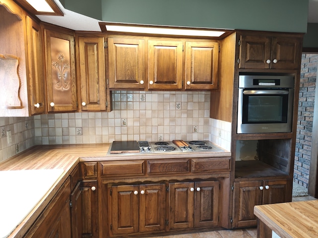 kitchen with backsplash, appliances with stainless steel finishes, light countertops, and brown cabinets