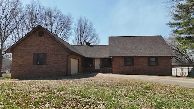 traditional-style house featuring fence, roof with shingles, concrete driveway, a garage, and brick siding