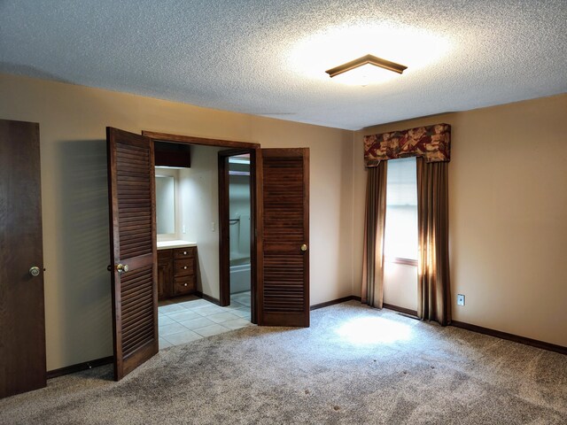 unfurnished bedroom with a textured ceiling, baseboards, and light carpet