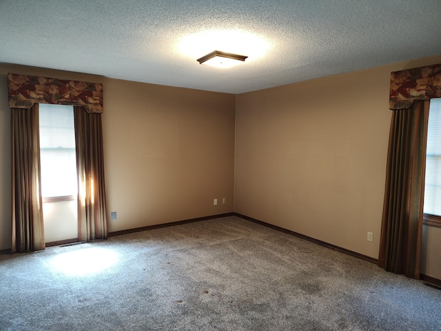 carpeted empty room featuring baseboards and a textured ceiling