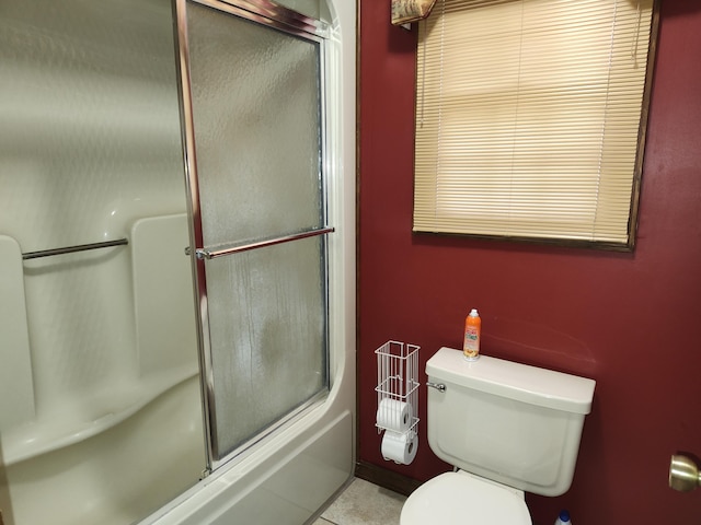 bathroom with toilet and shower / bath combination with glass door