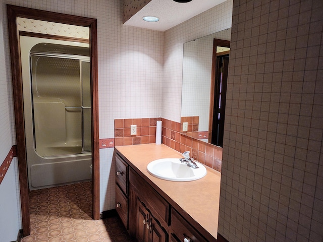 bathroom with tile patterned floors, tile walls, wallpapered walls, enclosed tub / shower combo, and vanity