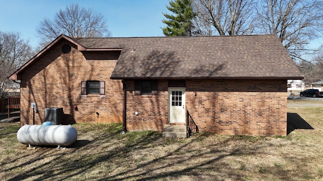 rear view of property with a yard, brick siding, and a shingled roof