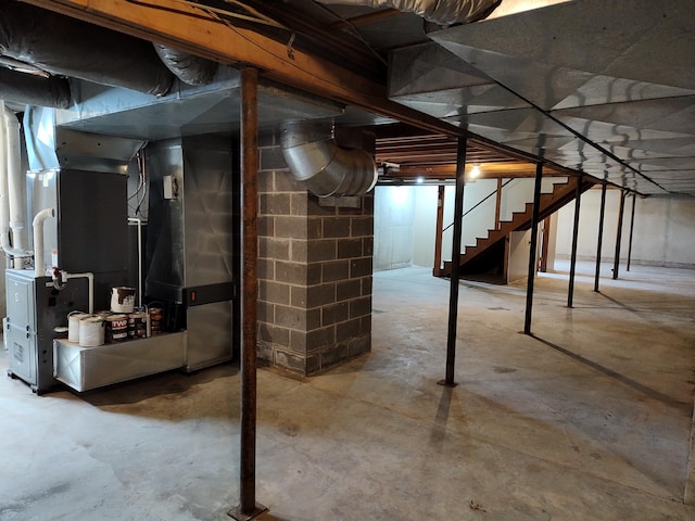 unfinished basement featuring stairway and heating unit