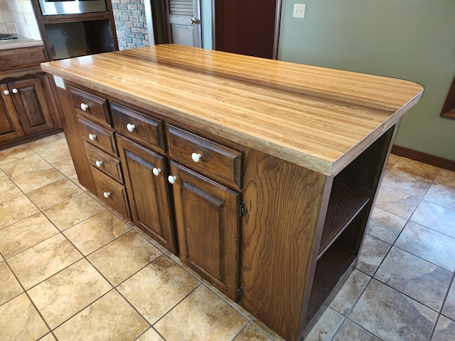 kitchen featuring open shelves, wood counters, a kitchen island, stovetop, and light tile patterned flooring