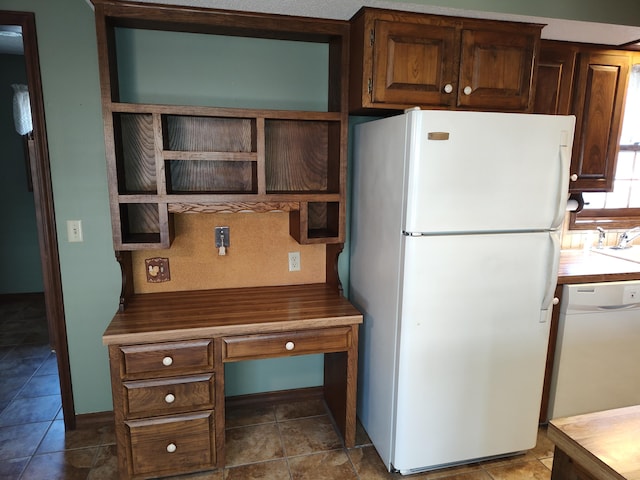 kitchen with open shelves, white appliances, dark tile patterned flooring, and a sink