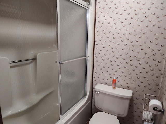 bathroom with enclosed tub / shower combo, toilet, and wallpapered walls